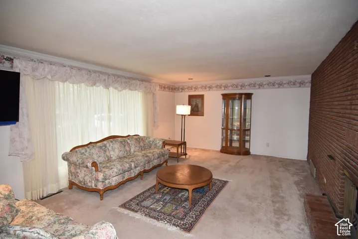 Living area featuring a floor-to-ceiling brick fireplace, recessed lighting, and a large window with floor-length drapery