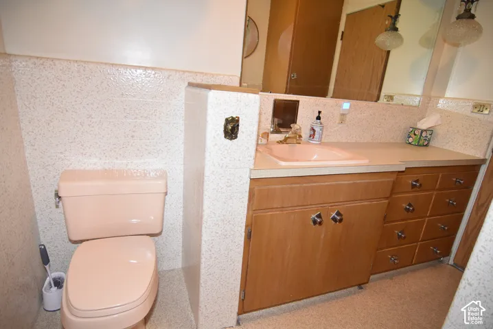 Built-in vanity featuring wood-finish cabinetry, a solid-surface countertop with an integrated basin, expansive wall-to-wall mirror, and textured wall surfacing