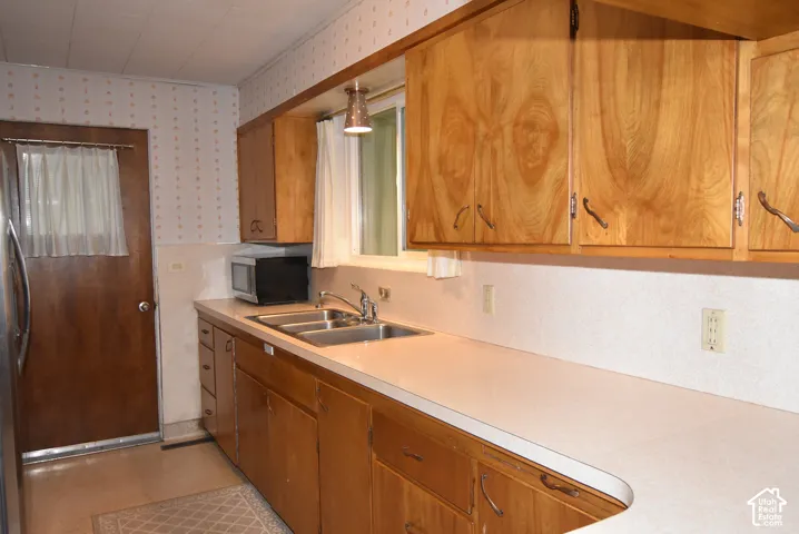 Kitchen featuring wood cabinetry, solid-surface countertops, dual-basin stainless steel sink, and a door with a glass insert