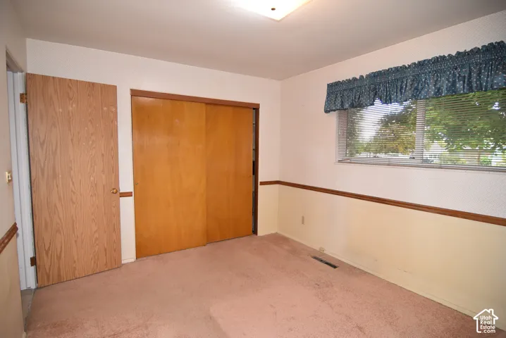 Bedroom #1 featuring wood-finish sliding closet doors, wood-finish interior door, wall-to-wall carpeting, and chair rail molding