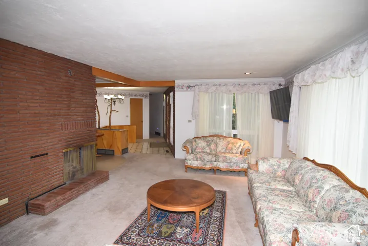 Full-height brick fireplace, wood-beam architectural accent, recessed lighting, and expansive windows