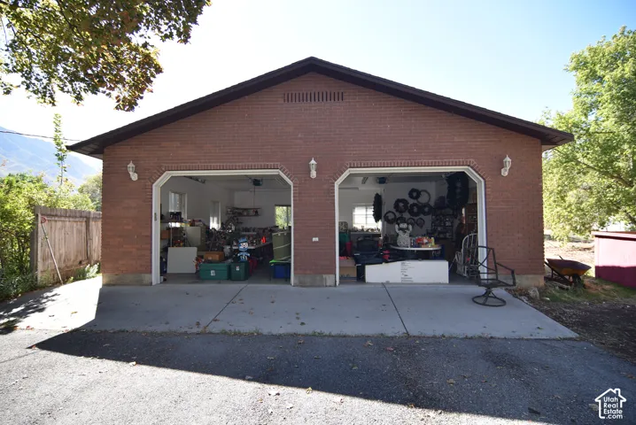 Detached two-car garage featuring a brick exterior, concrete driveway, and wall-mounted exterior light fixtures