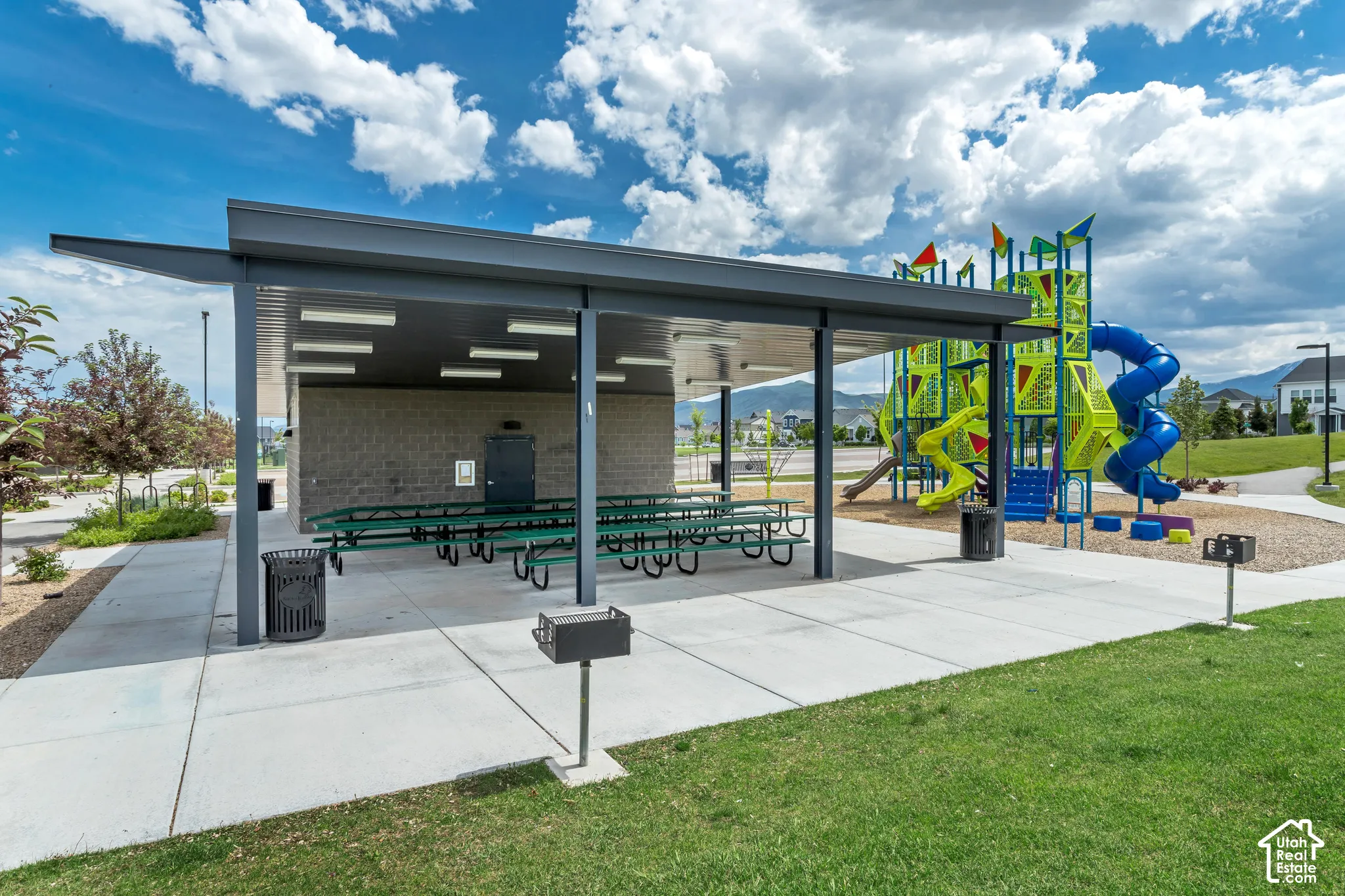 Covered pavilion featuring a concrete patio, integrated lighting, metal grills, and a multi-level playground structure