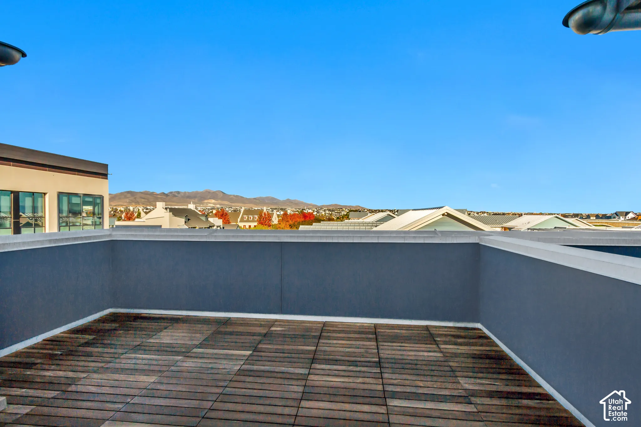 Rooftop terrace featuring wood-finish decking and solid privacy walls with mountain and horizon scenery