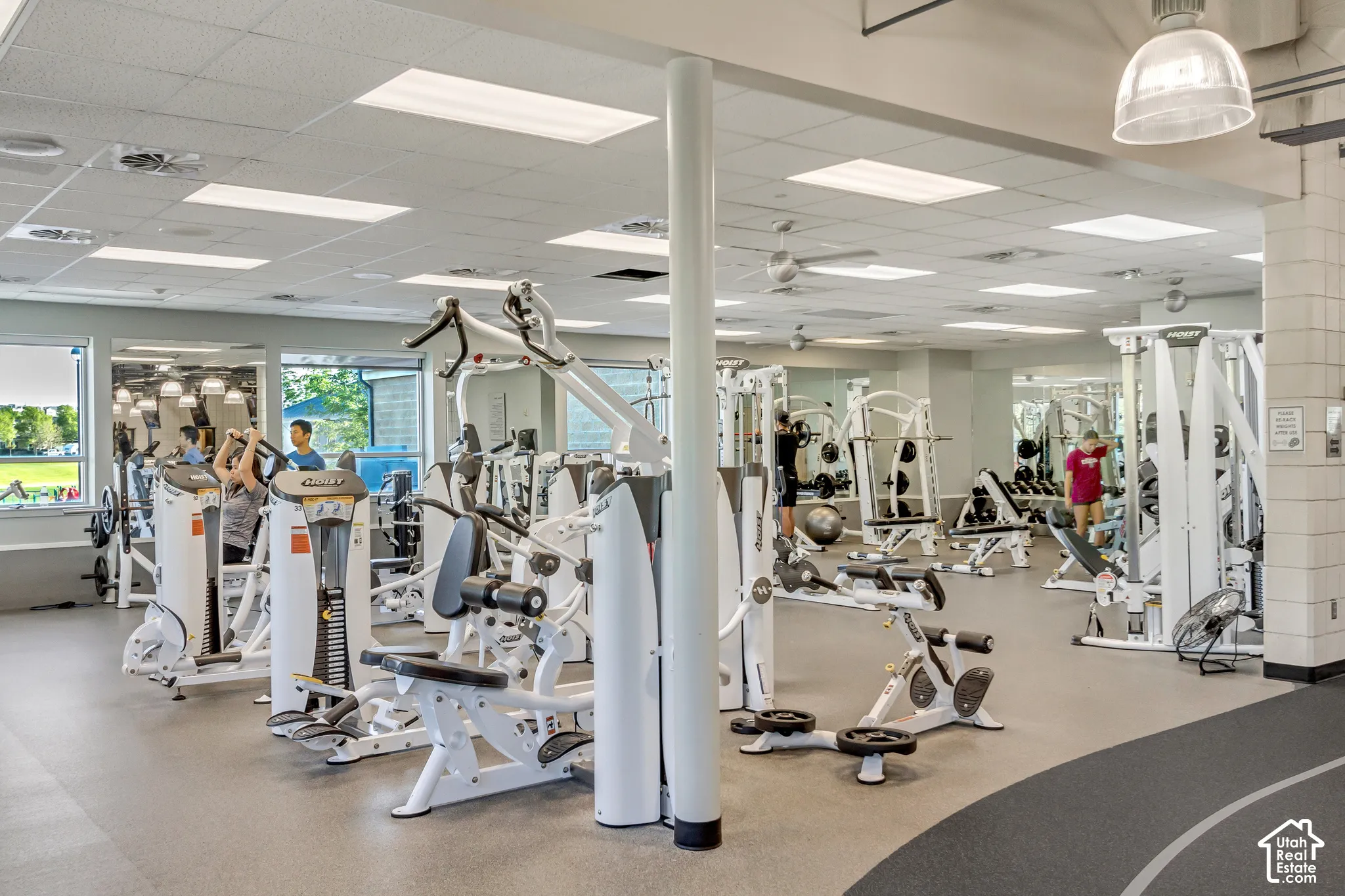 Fitness center featuring wall-to-wall mirrors, recessed and pendant lighting, and specialized rubberized flooring