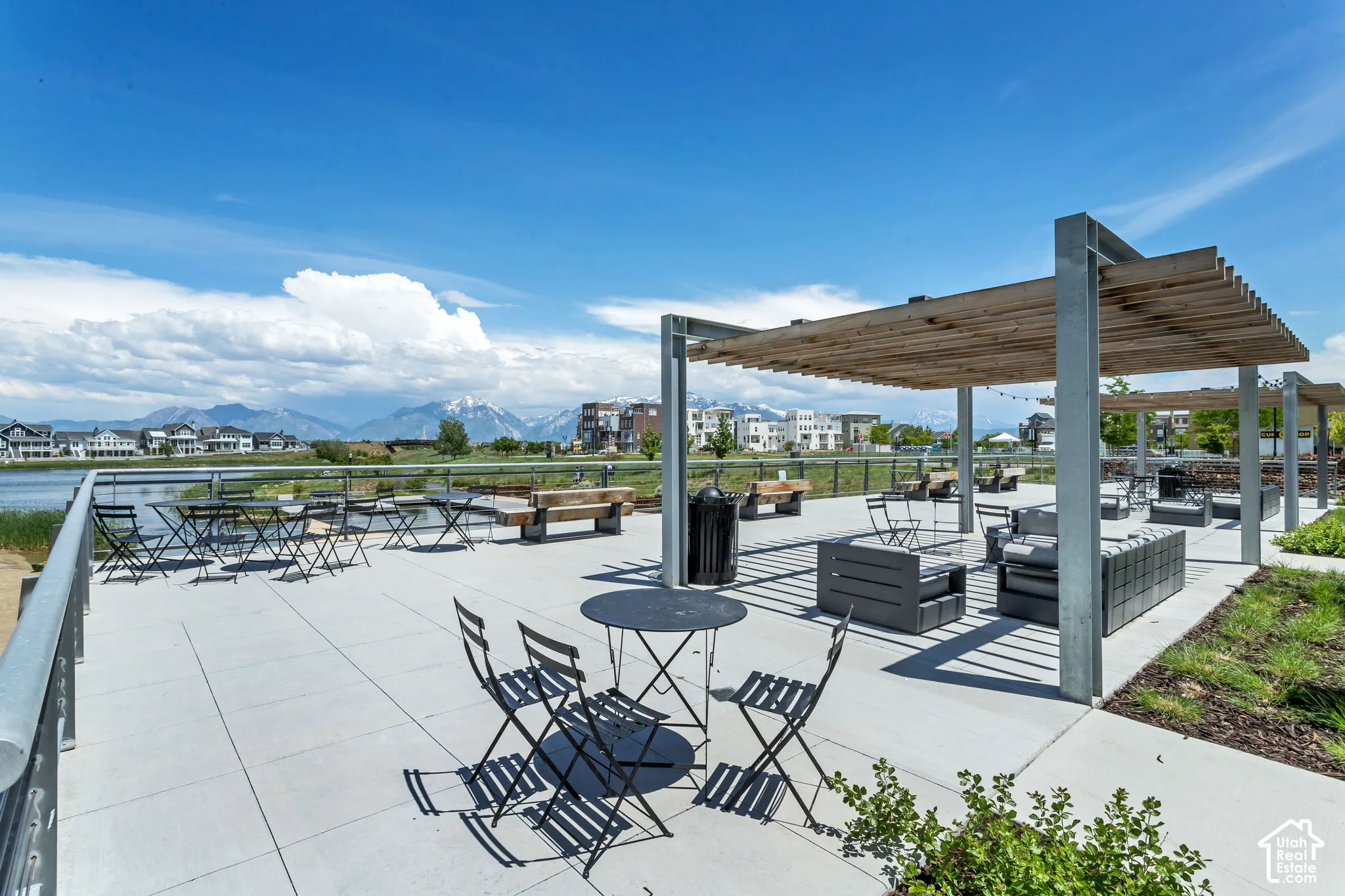 Expansive concrete terrace featuring dual wood-slat pergolas with steel framing and a metal perimeter railing