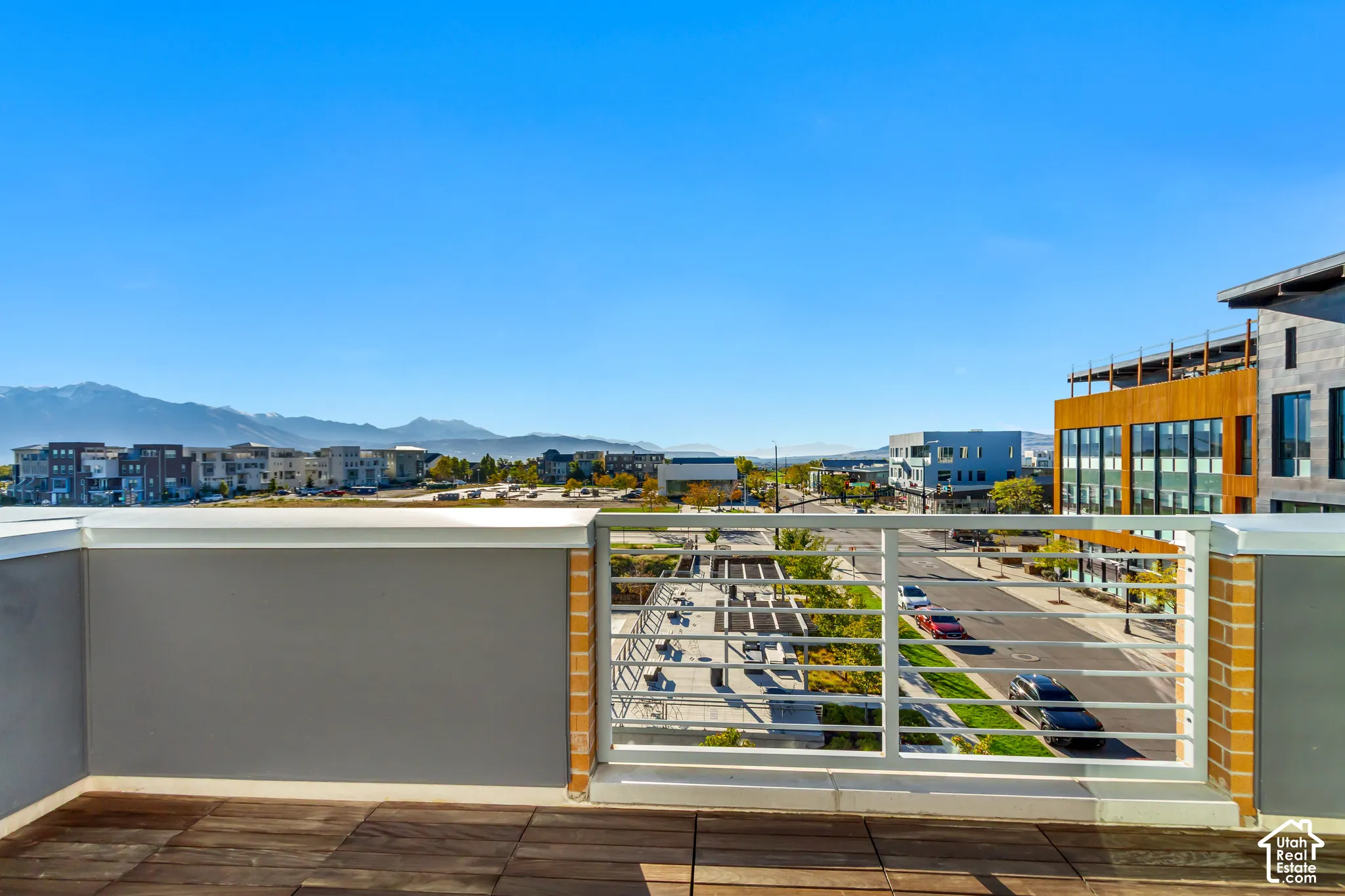 Rooftop deck featuring wood-finish decking, horizontal metal railings, and mountain scenery