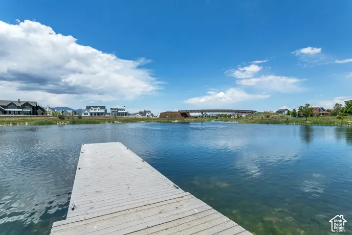 Waterfront setting featuring a stationary wood-plank dock, natural shoreline vegetation, and mountain backdrop