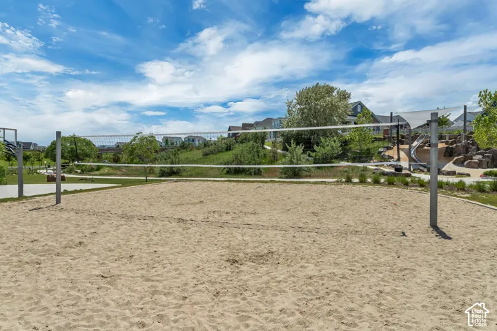 Sand volleyball court featuring a permanent net system, metal posts, and surrounding landscaped grounds with rock features