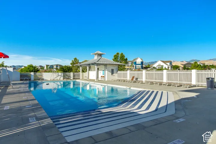 Swimming pool featuring a concrete deck, built-in steps, and a covered pavilion with metal roofing, enclosed by perimeter fencing