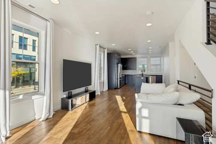 Open concept interior featuring wood-finish flooring, recessed lighting, and a modern kitchen with dark cabinetry