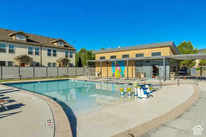Outdoor swimming pool featuring a zero-depth entry, built-in water play features, concrete pool deck, and a metal pergola structure