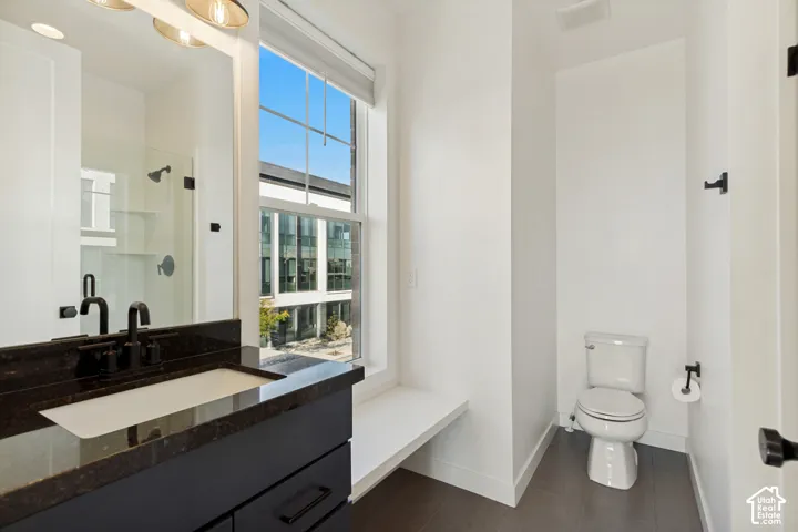 Dark-toned vanity with a rectangular sink, stone-composite countertop, matte black fixtures, glass-enclosed shower, and built-in window bench