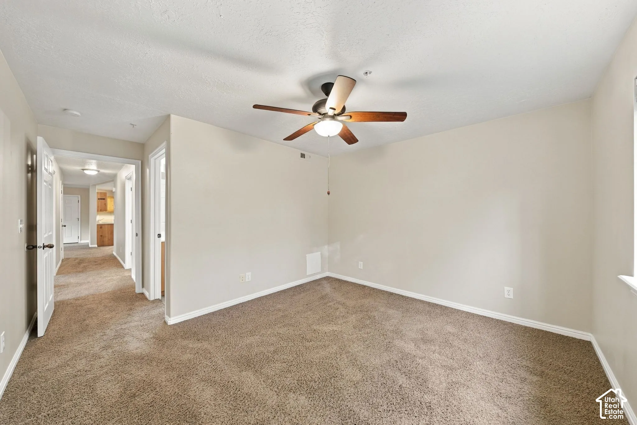 Neutral interior space featuring carpeted flooring, a ceiling-mounted fan with integrated light fixture, and solid-core paneled doors