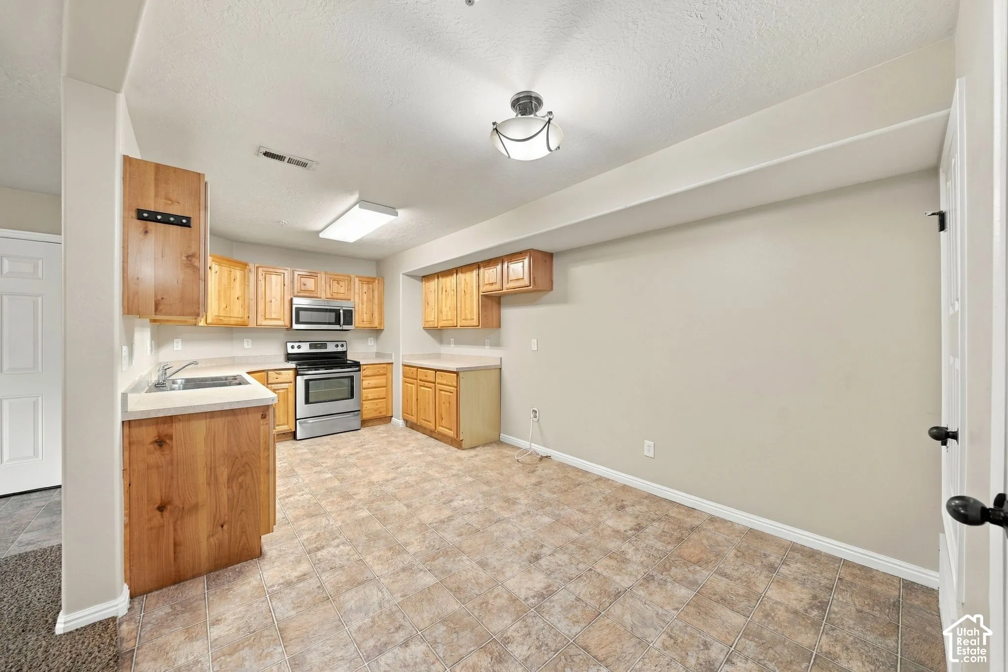 Kitchen featuring wooden cabinetry, stainless steel oven, built-in microwave, solid surface countertops, and tile flooring