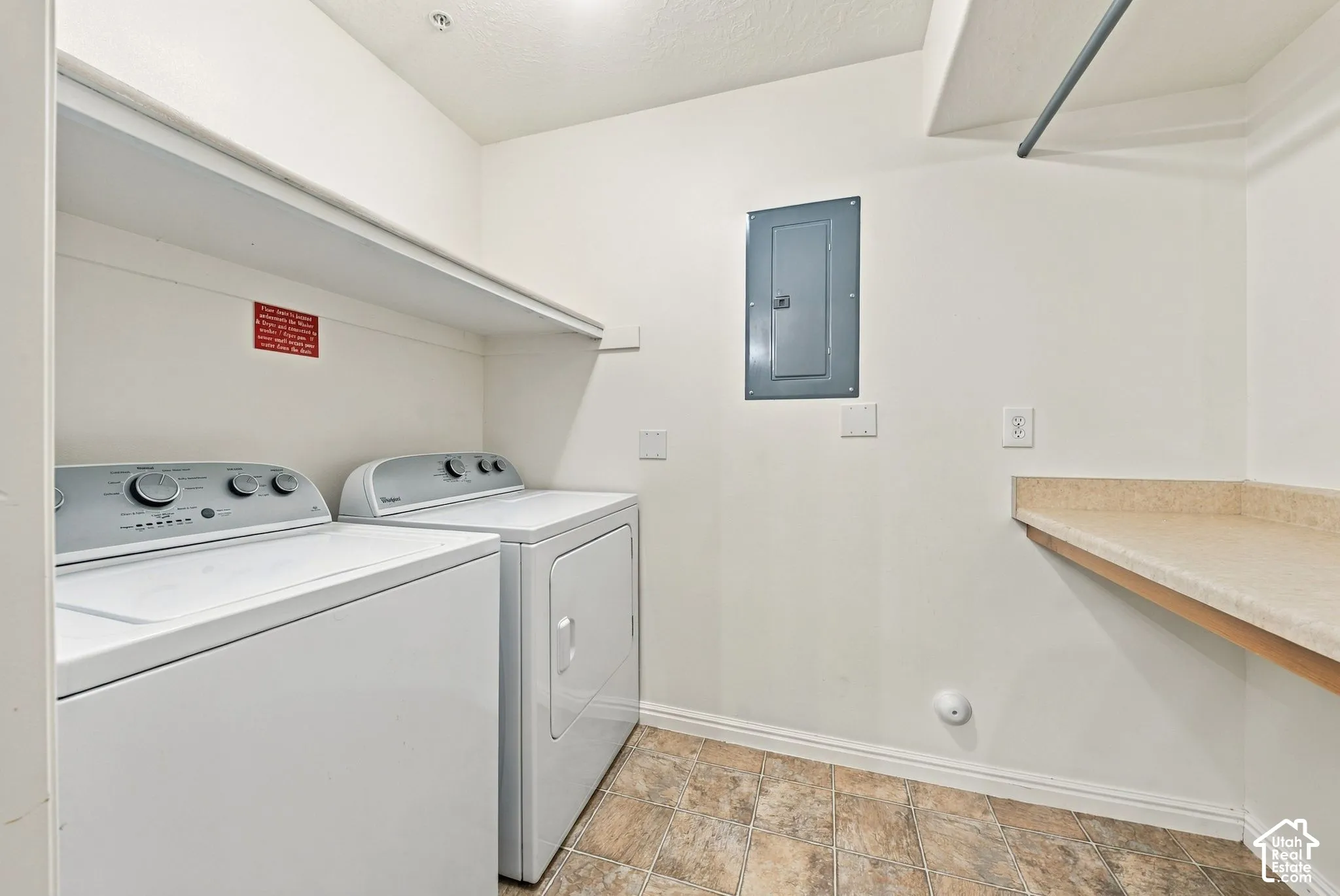 Laundry space featuring a laminate countertop, built-in shelving, a metal clothes rod, and resilient tile flooring