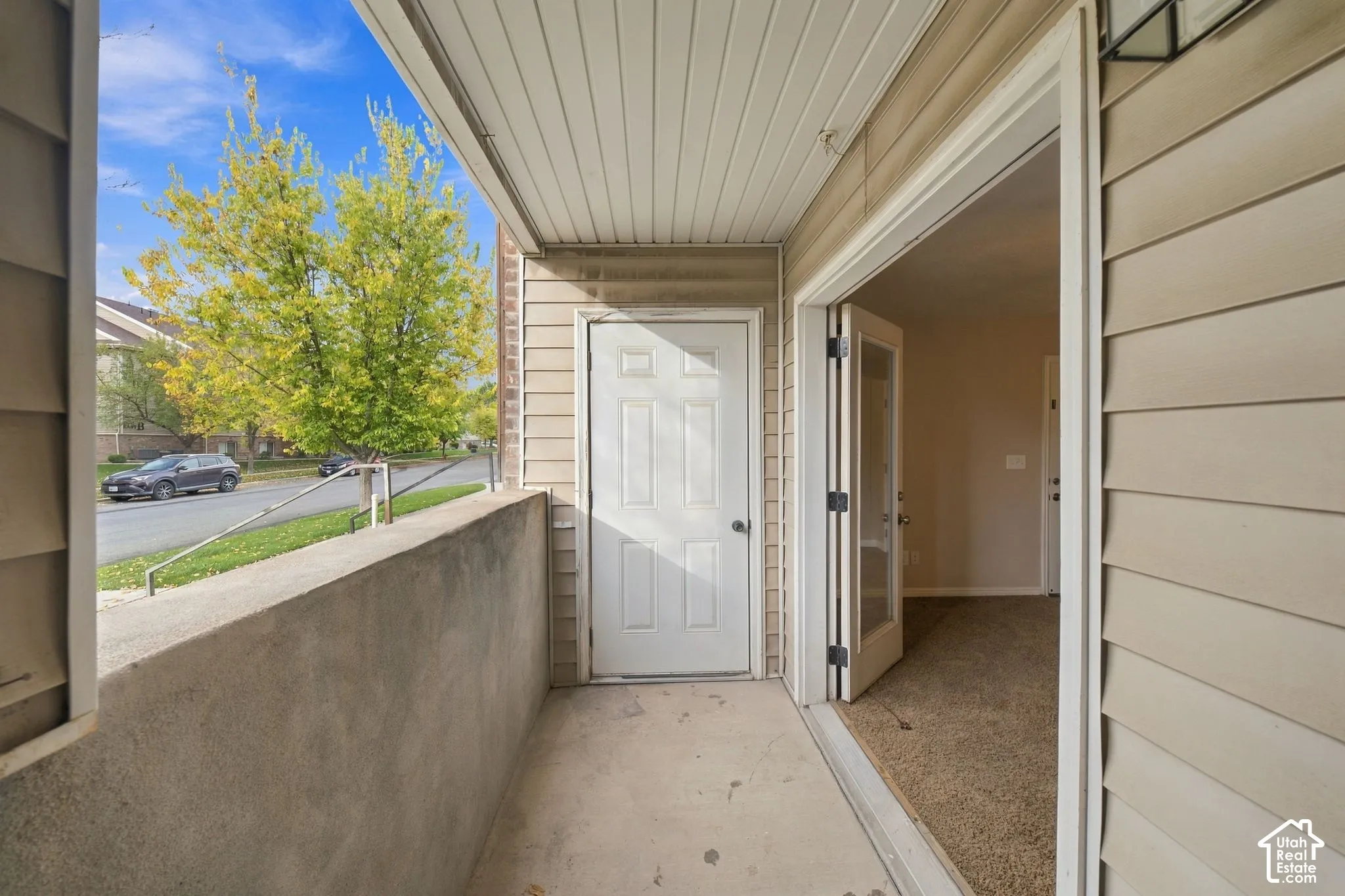 Covered patio featuring concrete flooring, a solid panel entry door, horizontal vinyl siding, and a hinged glass-pane door