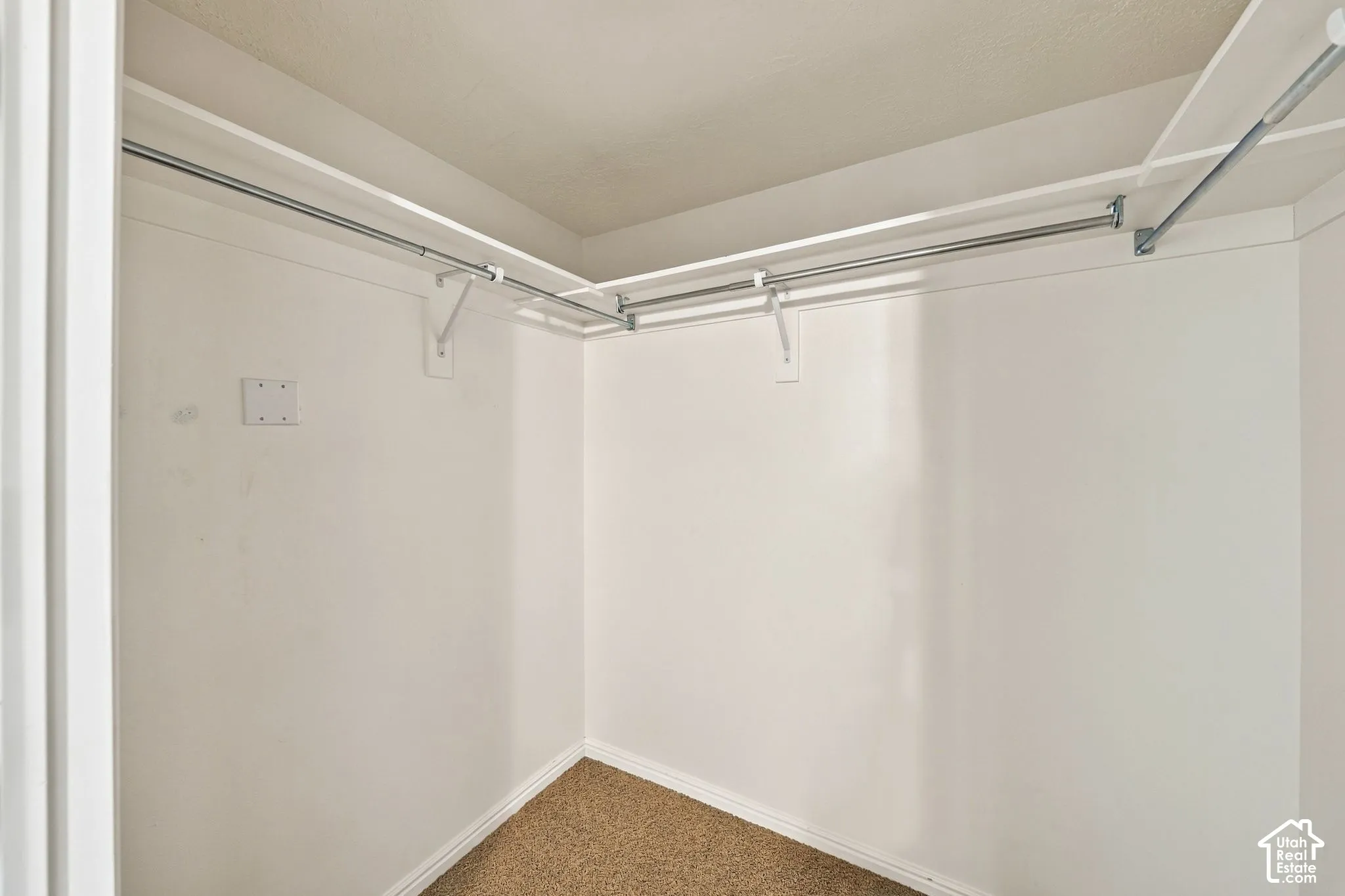 Walk-in closet featuring neutral carpeting and built-in metal shelving rods