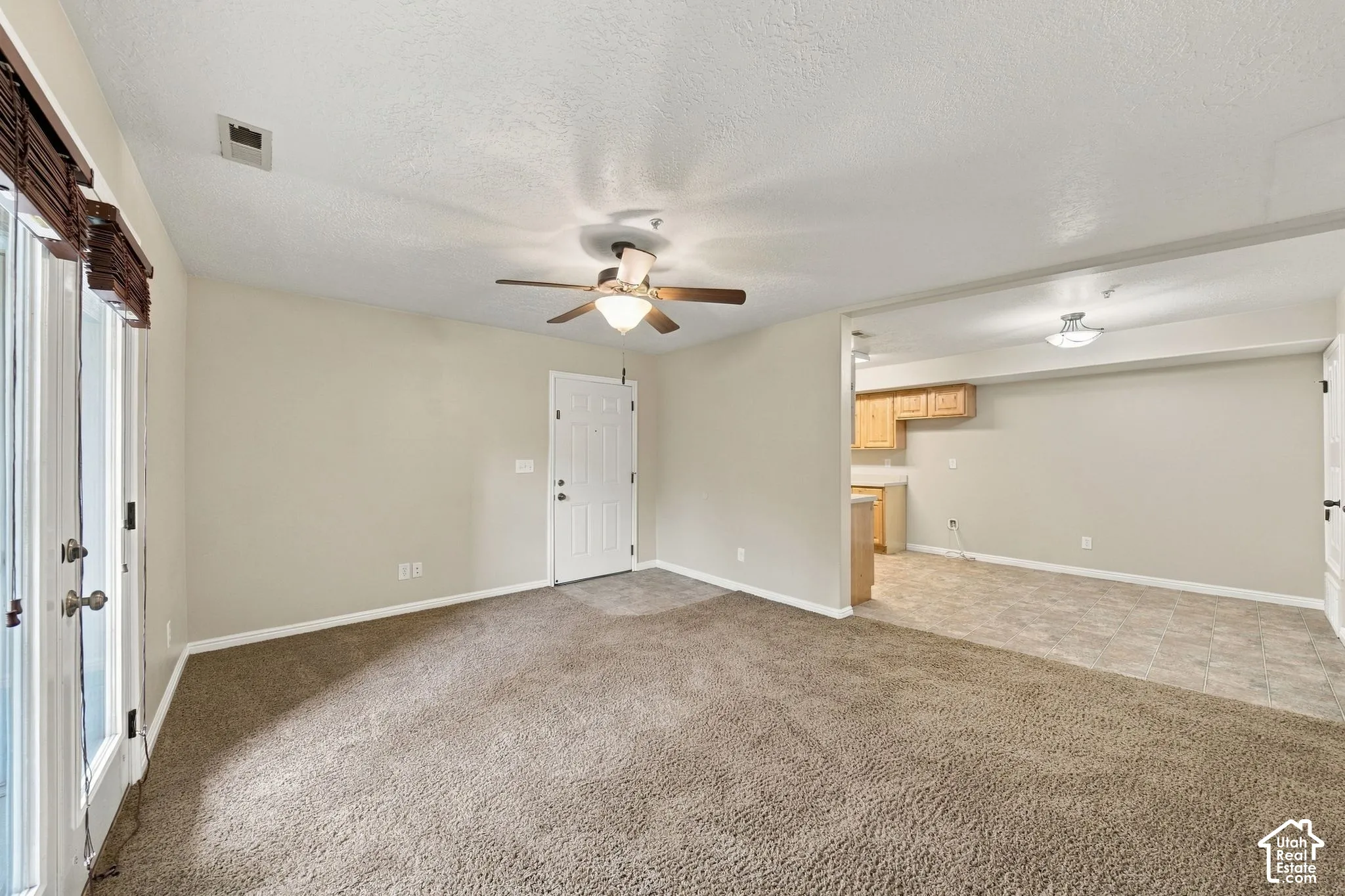 Interior featuring neutral wall paint, carpeted flooring, a ceiling fan with integrated lighting, and a glass-paned exterior door