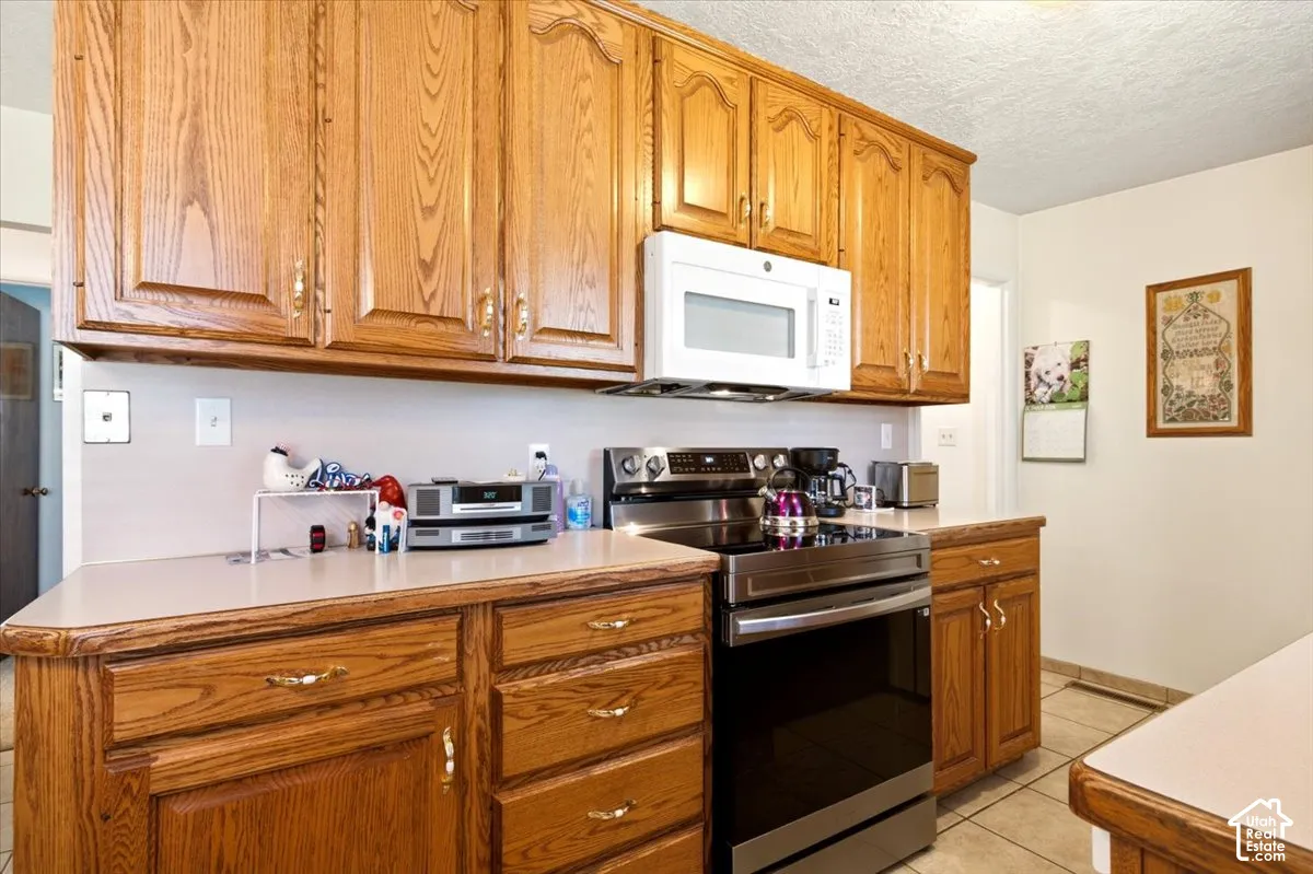 Kitchen featuring solid wood cabinetry, neutral countertops, stainless steel slide-in range, and over-the-range microwave