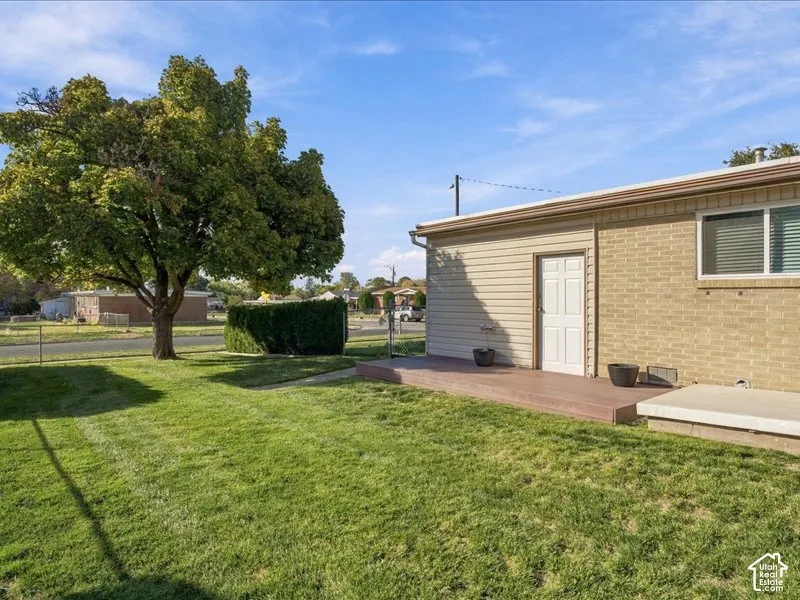 Exterior featuring a brick and siding facade, a raised composite deck, a concrete patio slab, and a mature shade tree set within a grass lawn