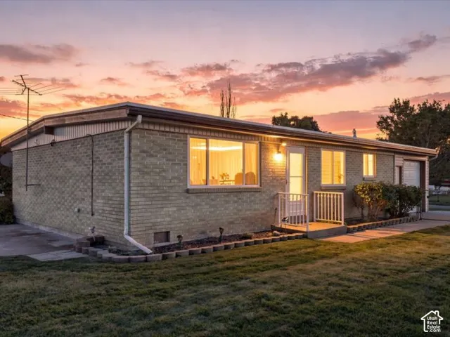 Single-story brick exterior featuring a low-slope roofline, concrete walkway, and integrated garage