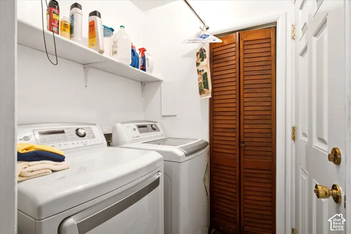 Laundry space featuring built-in shelving, a wall-mounted clothing rod, and wood-finish louvered bi-fold doors