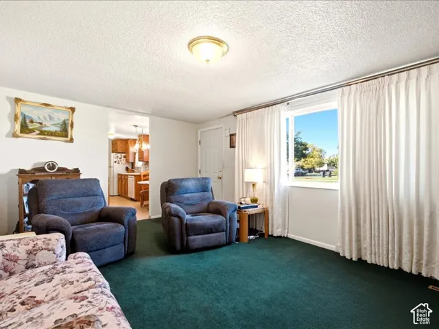 Living area featuring wall-to-wall carpeting, a large picture window, and a flush-mount ceiling light fixture