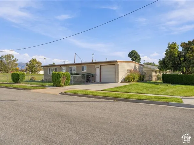 Single-story residence featuring a brick and horizontal siding exterior, an attached one-car garage, a concrete driveway, and a chain-link fenced yard
