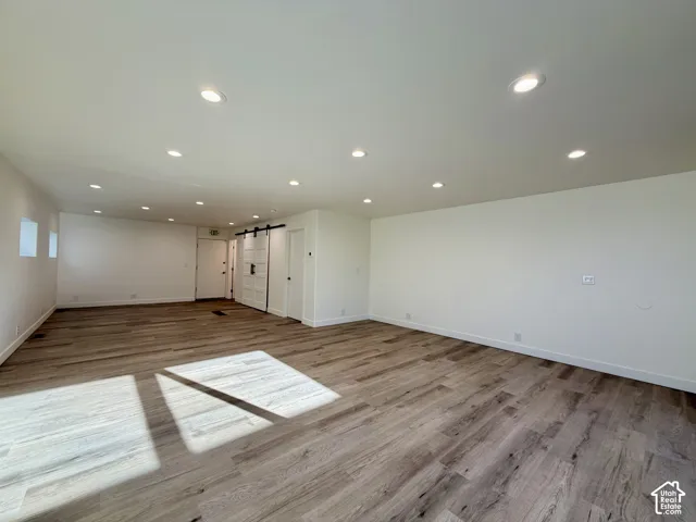 Open-concept room featuring wood-finish flooring, recessed lighting, and a sliding barn door