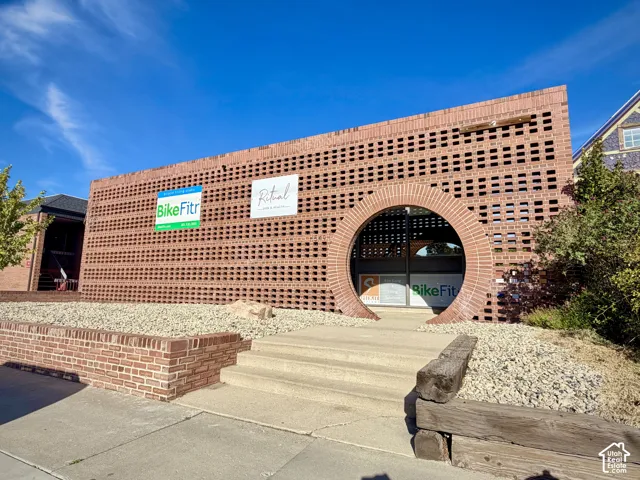 Exposed brick exterior featuring a decorative lattice pattern, a prominent circular masonry entryway, and tiered concrete stairs