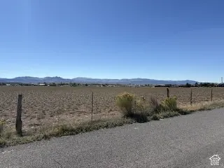 Expansive parcel of level land featuring a wire-and-post perimeter fence and mountain backdrop