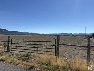 Expansive acreage featuring wire fencing, a metal gate, and mountain scenery