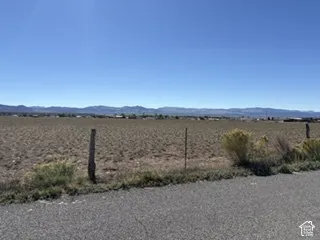 Level lot featuring desert terrain, perimeter wire fencing, and expansive mountain scenery