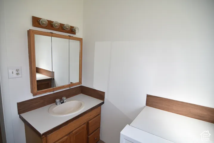 Wood-cabinet vanity featuring a solid-surface countertop, integrated basin, four-light wall-mounted fixture, and a tri-fold medicine cabinet