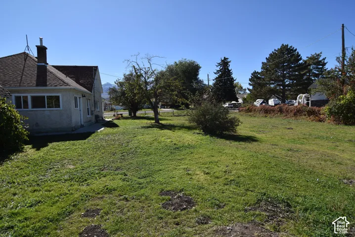 Expansive lot featuring mature trees, mountain backdrop, and concrete patio