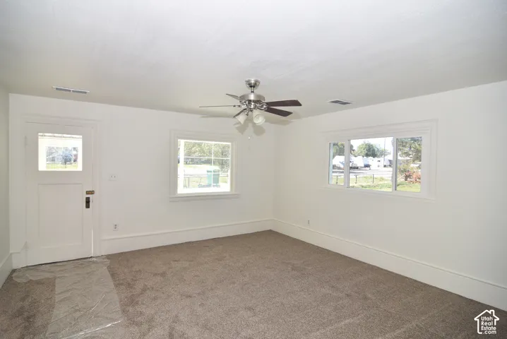 Neutral-toned carpeting, multi-pane windows, and a ceiling-mounted light fixture with a fan