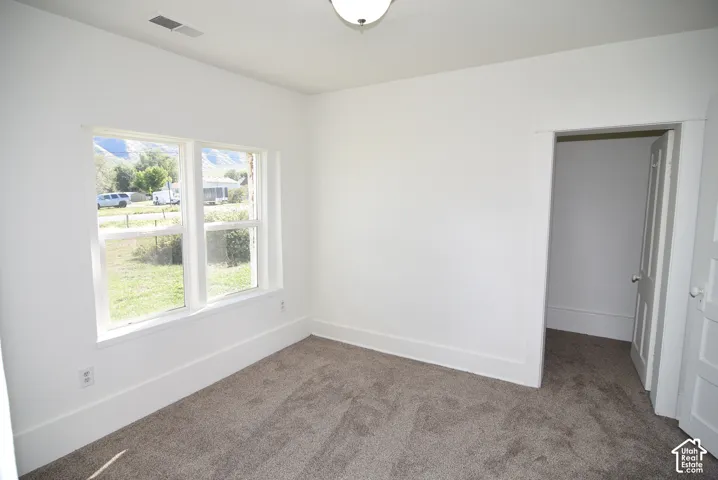 Neutral interior space featuring carpeting, white walls, wide door casing, and a multi-pane window with mountain scenery