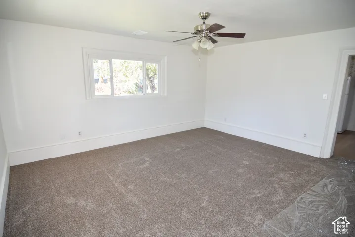 Neutral-toned wall-to-wall carpeting, white walls, and a ceiling-mounted light fixture with a multi-blade fan