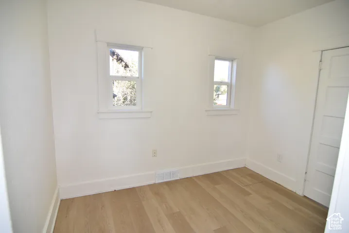 Interior space featuring wood-finish flooring, two windows with traditional wood casing, and a four-panel interior door