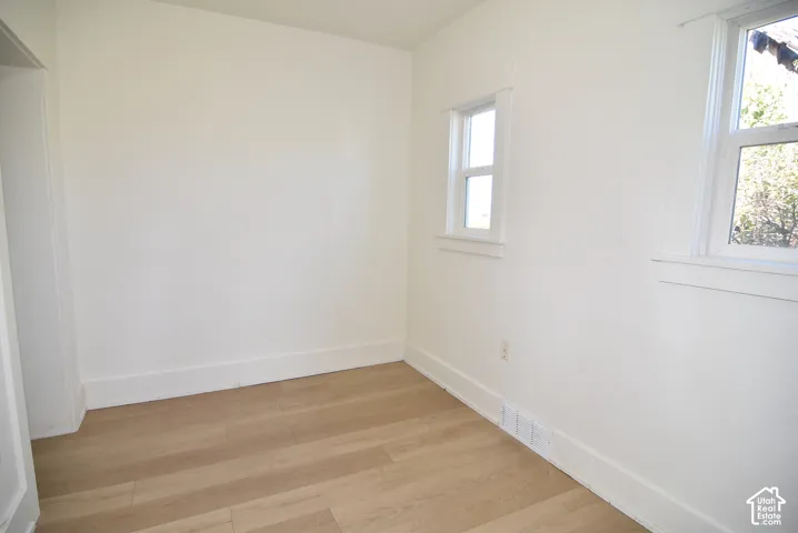 Interior room featuring wood-finish flooring, white walls, and two double-hung windows with white casing