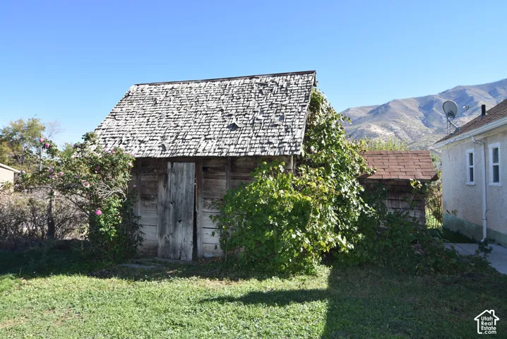 Outbuilding with wood-plank siding, shake roofing, and mountain backdrop