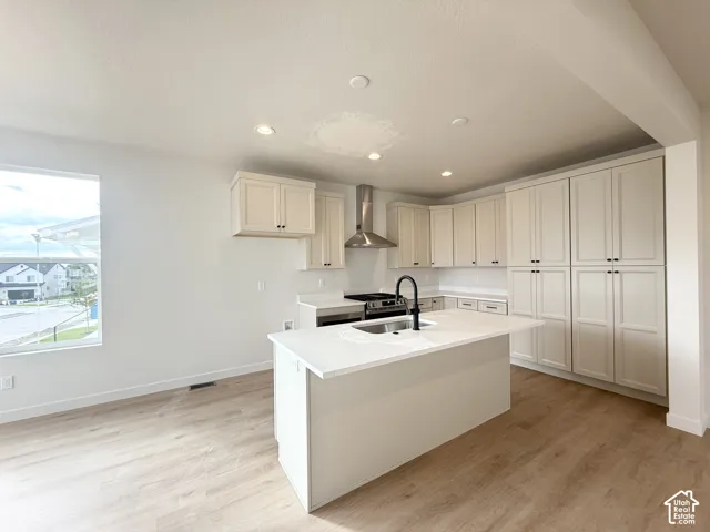 Kitchen featuring white shaker-style cabinetry, quartz countertops, a central island with an undermount sink, matte black faucet, and wood-finish flooring