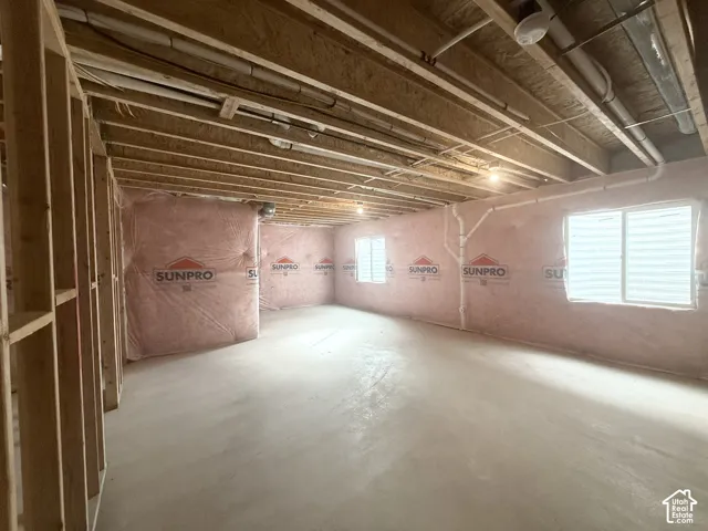 Unfinished lower level featuring exposed wood joist ceilings, concrete flooring, perimeter insulation, and dual sliding windows