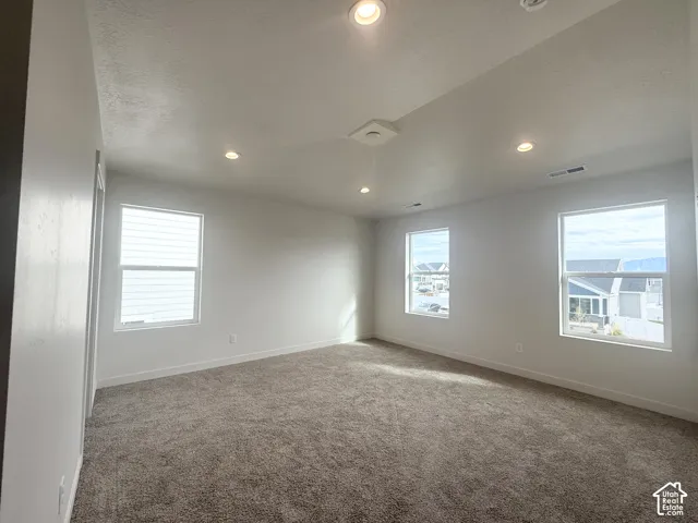 Neutral interior space featuring high ceilings, recessed lighting, wall-to-wall carpeting, and multiple windows providing natural light