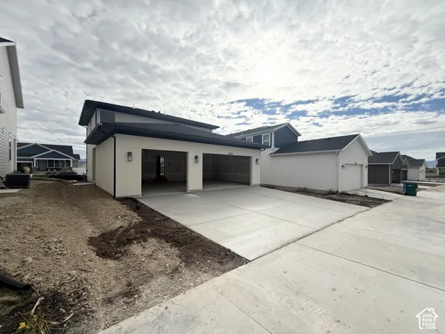 Attached three-car garage featuring a concrete driveway, smooth exterior stucco finish, and recessed wall-mounted lighting