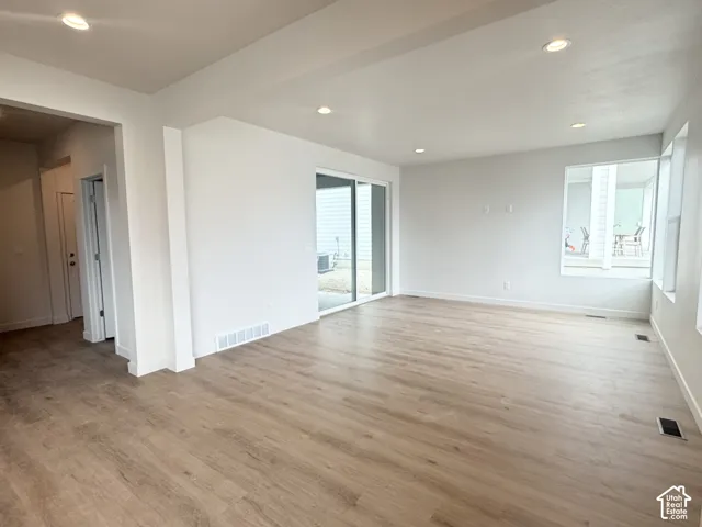 Open-concept interior featuring light wood-finish flooring, recessed lighting, sliding glass door, and large picture windows