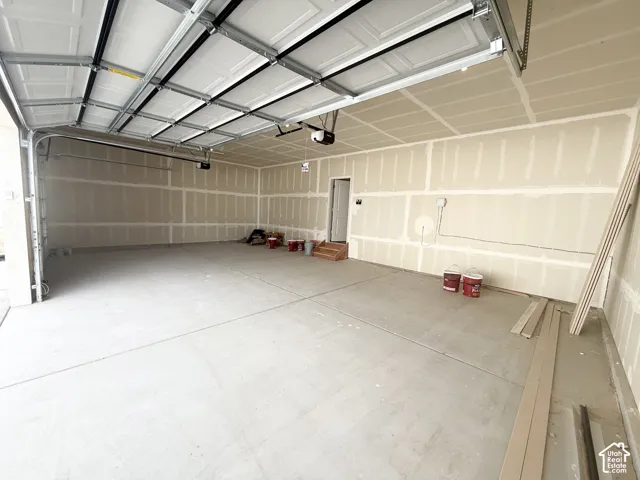 Multi-car garage featuring finished concrete flooring, drywall construction, and overhead door hardware