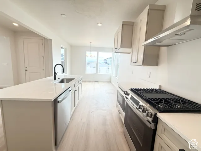 Kitchen featuring a central island with a quartz countertop, stainless steel gas range, stainless steel dishwasher, matte black faucet, and light-toned cabinetry