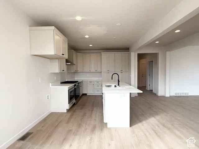 Kitchen featuring white cabinetry, wood-finish flooring, quartz-surface countertops, central island, and a matte black faucet